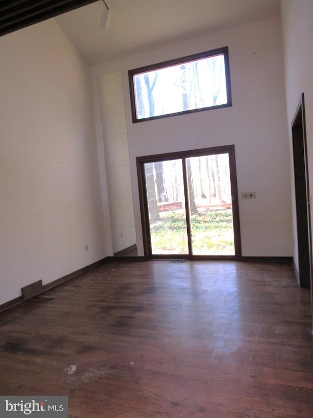 unfurnished living room featuring high vaulted ceiling and dark hardwood / wood-style floors