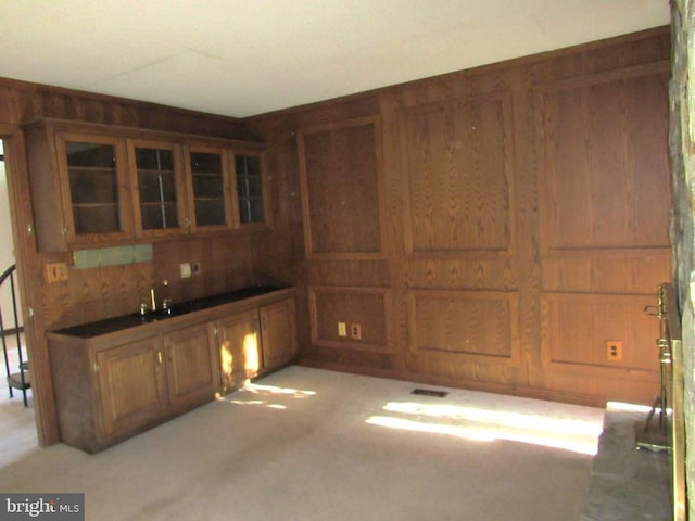 kitchen featuring light colored carpet and wooden walls