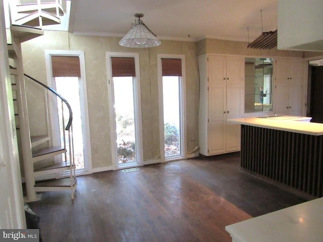 kitchen featuring white cabinets, dark hardwood / wood-style flooring, hanging light fixtures, and crown molding