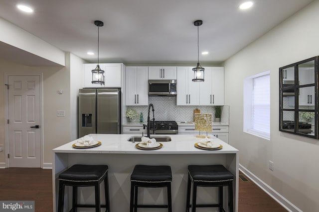 kitchen featuring white cabinetry, appliances with stainless steel finishes, a breakfast bar, and a center island with sink