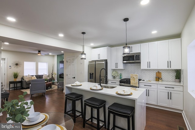 kitchen with sink, decorative light fixtures, a center island with sink, and appliances with stainless steel finishes