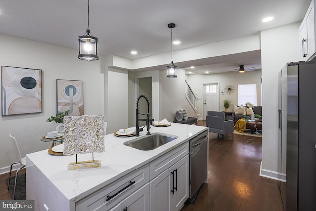 kitchen with dark wood-type flooring, sink, hanging light fixtures, an island with sink, and stainless steel appliances