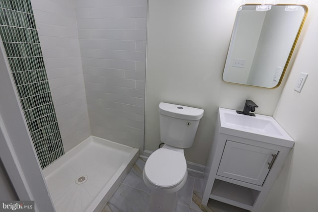 bathroom featuring a tile shower, vanity, and toilet