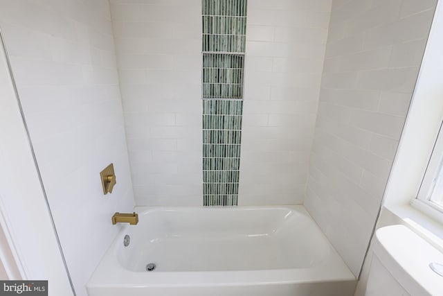 bathroom featuring tiled shower / bath combo and toilet