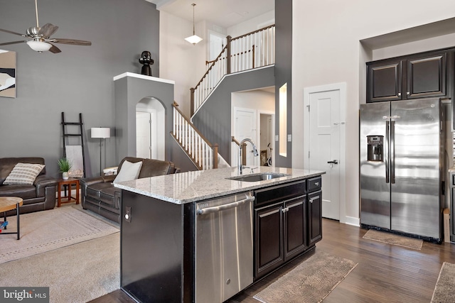 kitchen with a kitchen island with sink, a high ceiling, sink, dark hardwood / wood-style flooring, and stainless steel appliances