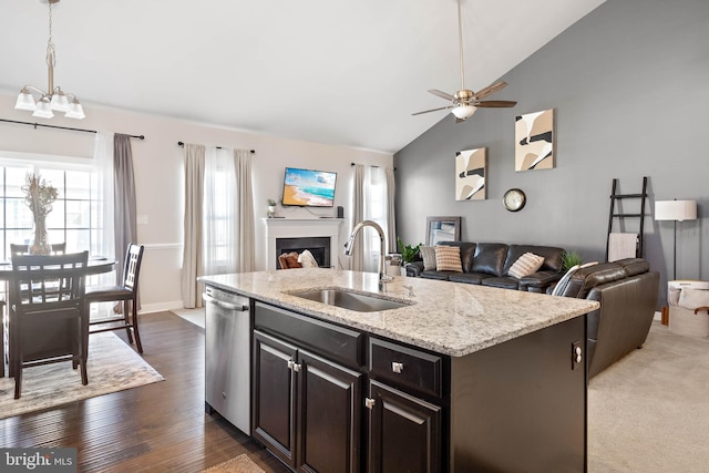 kitchen with sink, dark wood-type flooring, stainless steel dishwasher, vaulted ceiling, and a center island with sink