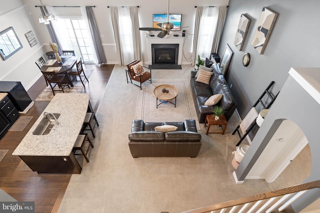 living room featuring hardwood / wood-style floors, ceiling fan with notable chandelier, and a healthy amount of sunlight