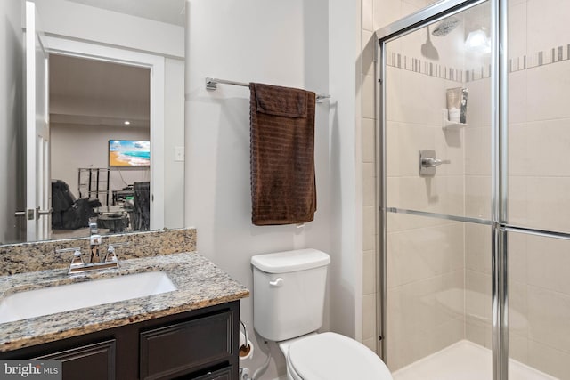 bathroom with vanity, toilet, and a shower with door