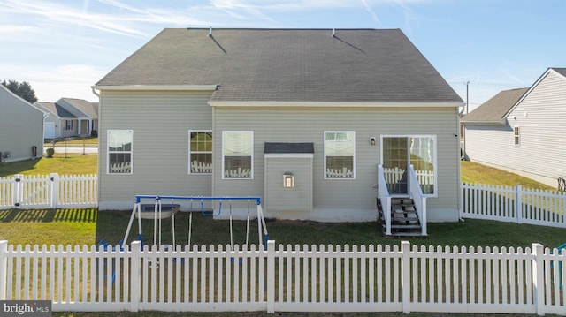 rear view of property featuring a yard and a trampoline