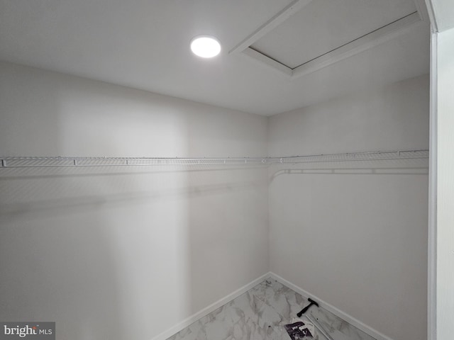 walk in closet featuring marble finish floor