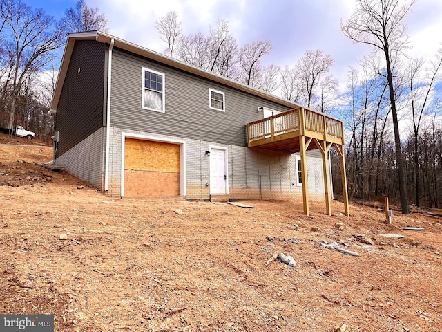 rear view of house with a garage, brick siding, and a wooden deck