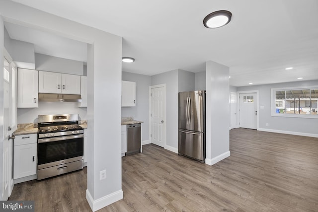 kitchen featuring white cabinets, stainless steel appliances, light stone countertops, and light hardwood / wood-style floors