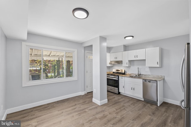 kitchen with appliances with stainless steel finishes, light stone counters, sink, light hardwood / wood-style flooring, and white cabinetry