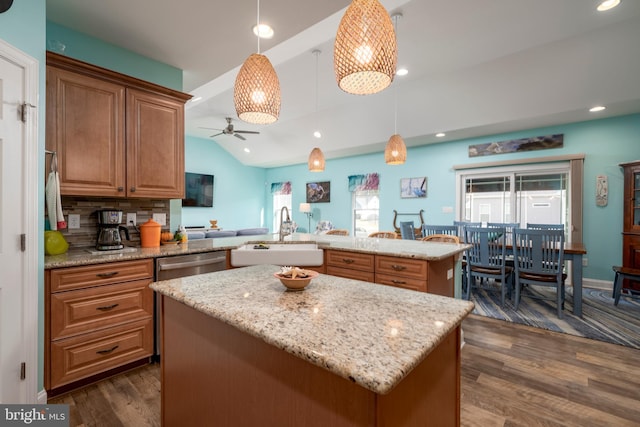 kitchen featuring pendant lighting, dark wood-type flooring, sink, a kitchen island, and kitchen peninsula