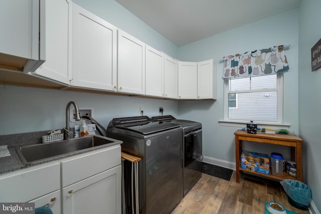 clothes washing area featuring separate washer and dryer, dark hardwood / wood-style floors, cabinets, and sink