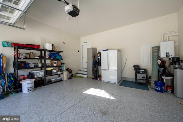 garage with tankless water heater, white fridge, and a garage door opener