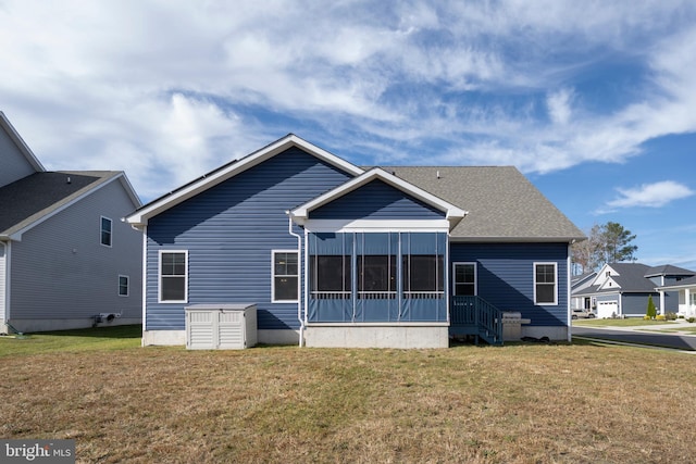 rear view of house featuring a lawn and a sunroom