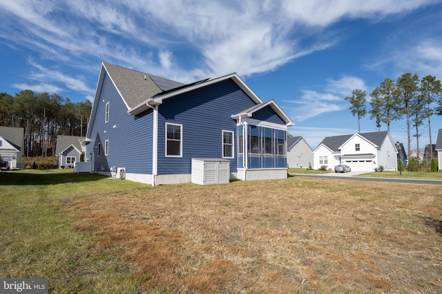 view of side of home with a lawn and a sunroom