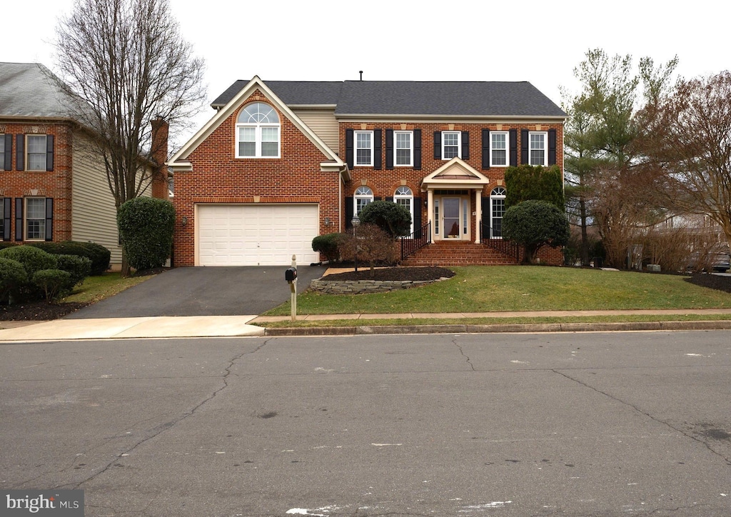 colonial home featuring a garage and a front yard