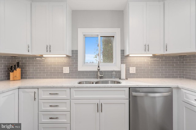 kitchen featuring white cabinets, dishwasher, light stone counters, and sink