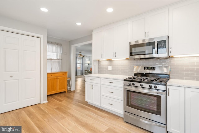 kitchen featuring white cabinetry, light hardwood / wood-style floors, light stone counters, and appliances with stainless steel finishes