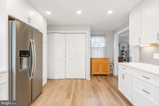 kitchen featuring stainless steel refrigerator with ice dispenser, light hardwood / wood-style flooring, decorative backsplash, light stone countertops, and white cabinetry