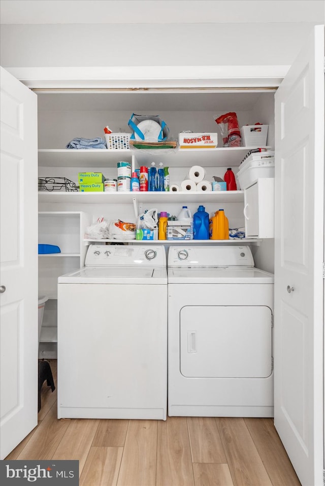 laundry area with light hardwood / wood-style flooring and washer and clothes dryer