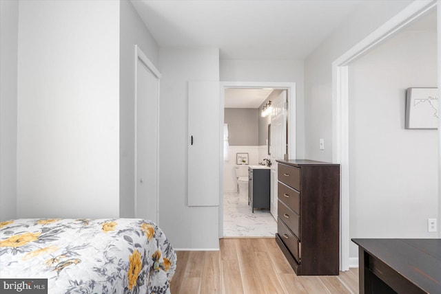 bedroom featuring light wood-type flooring and ensuite bath