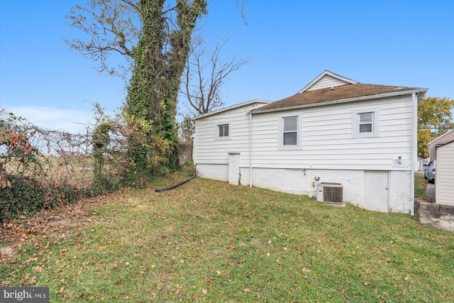 rear view of house with central air condition unit and a yard