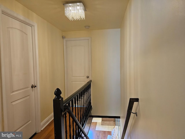 stairs with hardwood / wood-style floors and an inviting chandelier