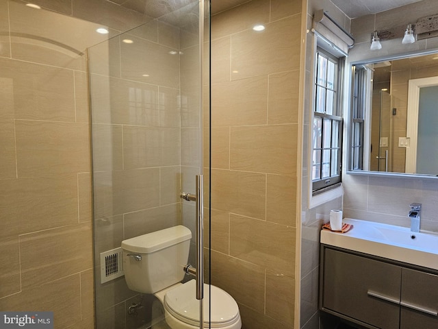 bathroom featuring vanity, toilet, tile walls, and a healthy amount of sunlight