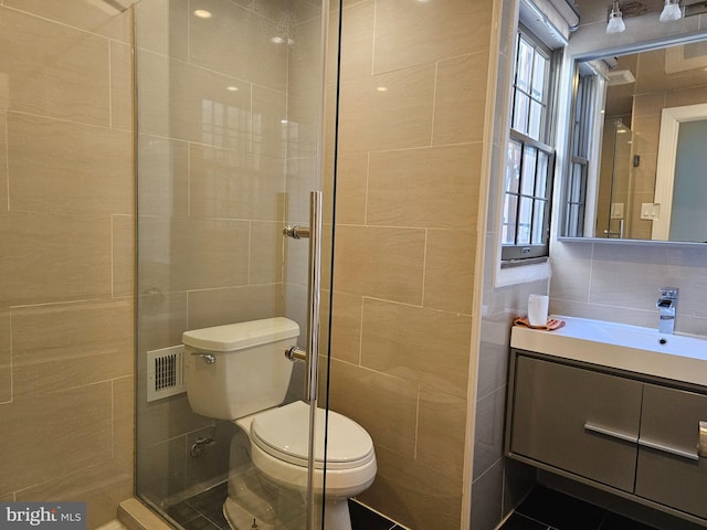 bathroom featuring walk in shower, vanity, tile walls, and toilet