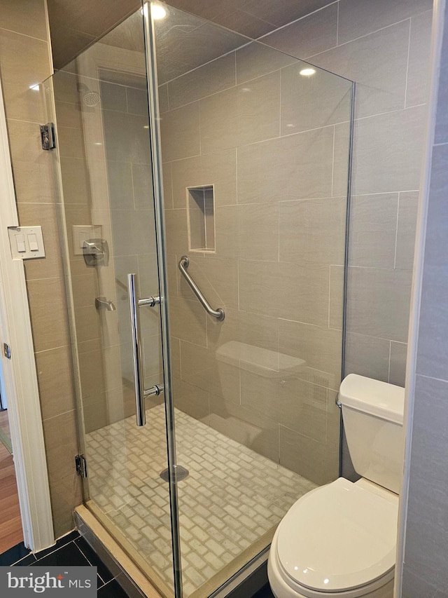 bathroom with a shower with shower door and toilet