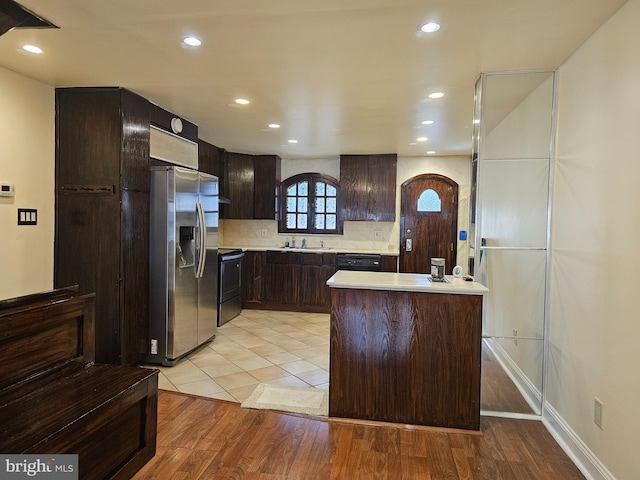 kitchen with black appliances, a center island, light wood-type flooring, and sink