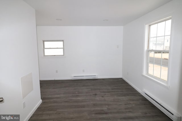 spare room with dark hardwood / wood-style flooring, plenty of natural light, and a baseboard heating unit