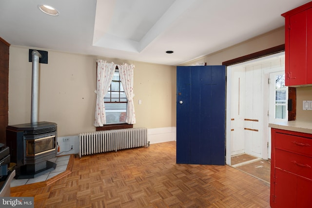 kitchen featuring a wood stove, light parquet flooring, ornamental molding, and radiator