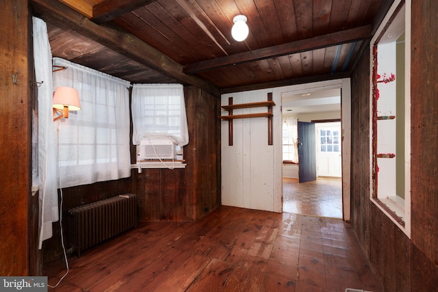 unfurnished room with wood walls, dark wood-type flooring, radiator, beamed ceiling, and wood ceiling