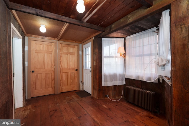 foyer with wood walls, radiator, beam ceiling, dark hardwood / wood-style flooring, and wood ceiling