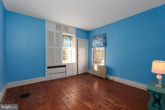 unfurnished bedroom with dark hardwood / wood-style flooring and radiator heating unit