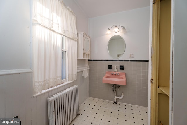 bathroom with sink, radiator, and tile walls