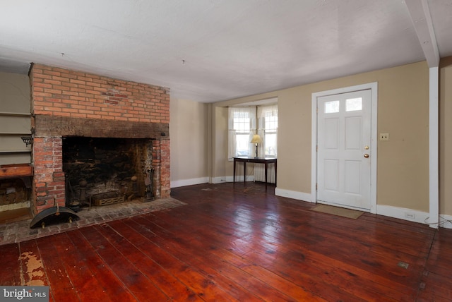 unfurnished living room featuring wood-type flooring, a brick fireplace, and beam ceiling