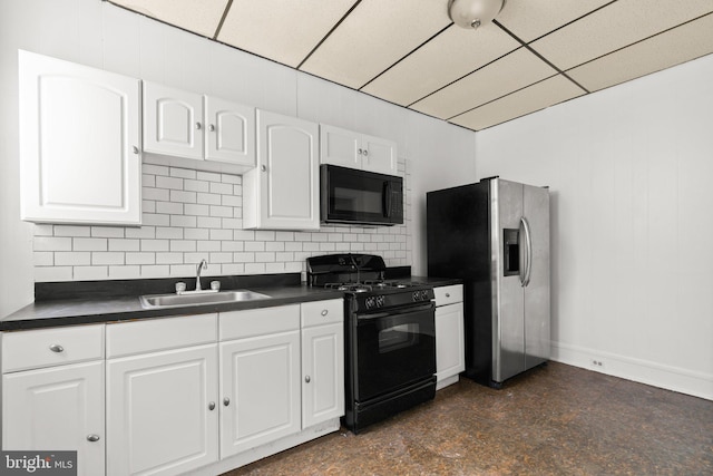 kitchen with a drop ceiling, black appliances, white cabinets, sink, and tasteful backsplash