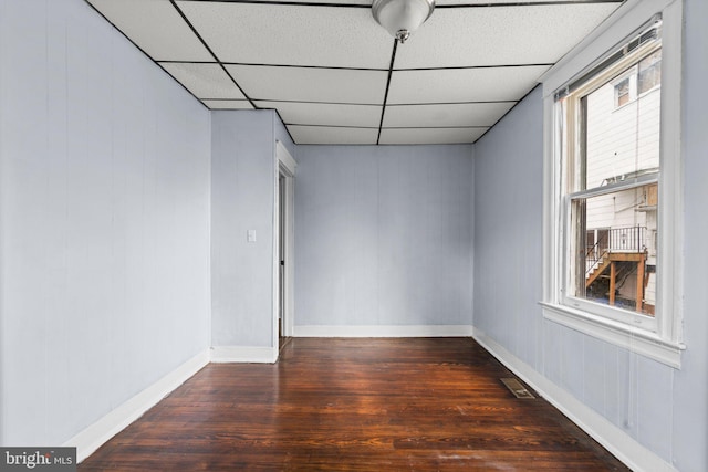 empty room featuring a paneled ceiling and dark wood-type flooring