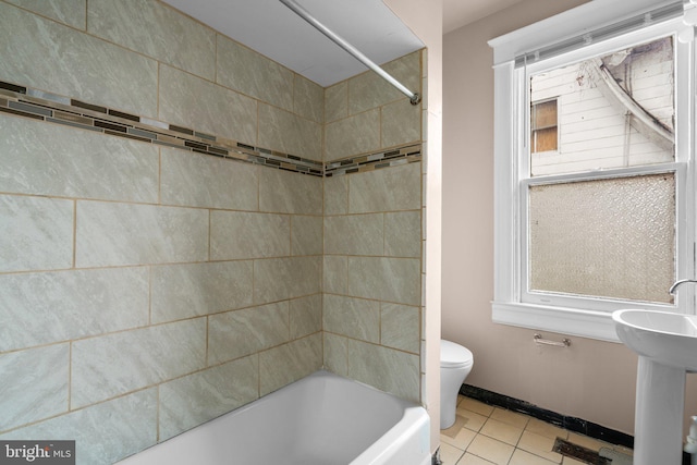 bathroom with tile patterned floors, tiled shower / bath combo, and toilet