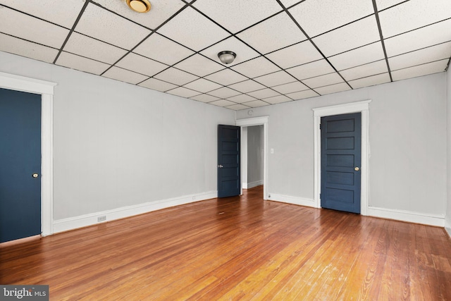 spare room with a paneled ceiling and hardwood / wood-style flooring