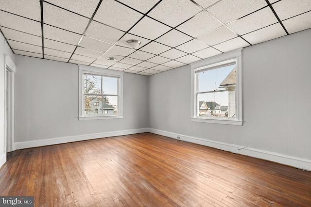 unfurnished room with hardwood / wood-style floors and a drop ceiling