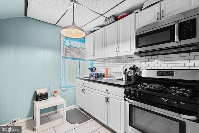 kitchen featuring backsplash, white cabinets, decorative light fixtures, and appliances with stainless steel finishes