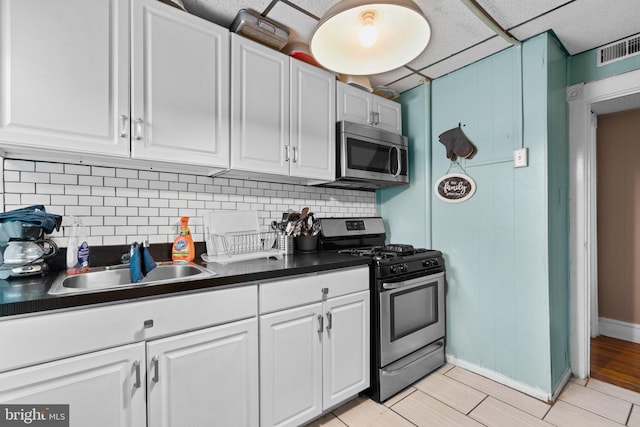 kitchen with white cabinets, sink, appliances with stainless steel finishes, tasteful backsplash, and light hardwood / wood-style floors