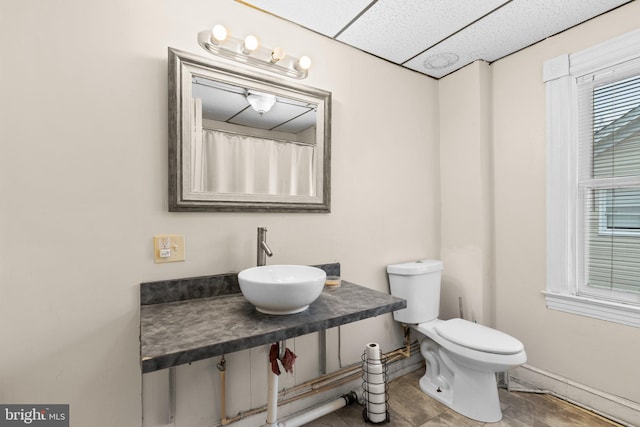 bathroom featuring a paneled ceiling, toilet, and sink