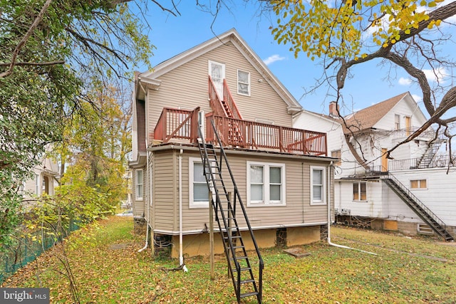 back of house with a balcony and a yard